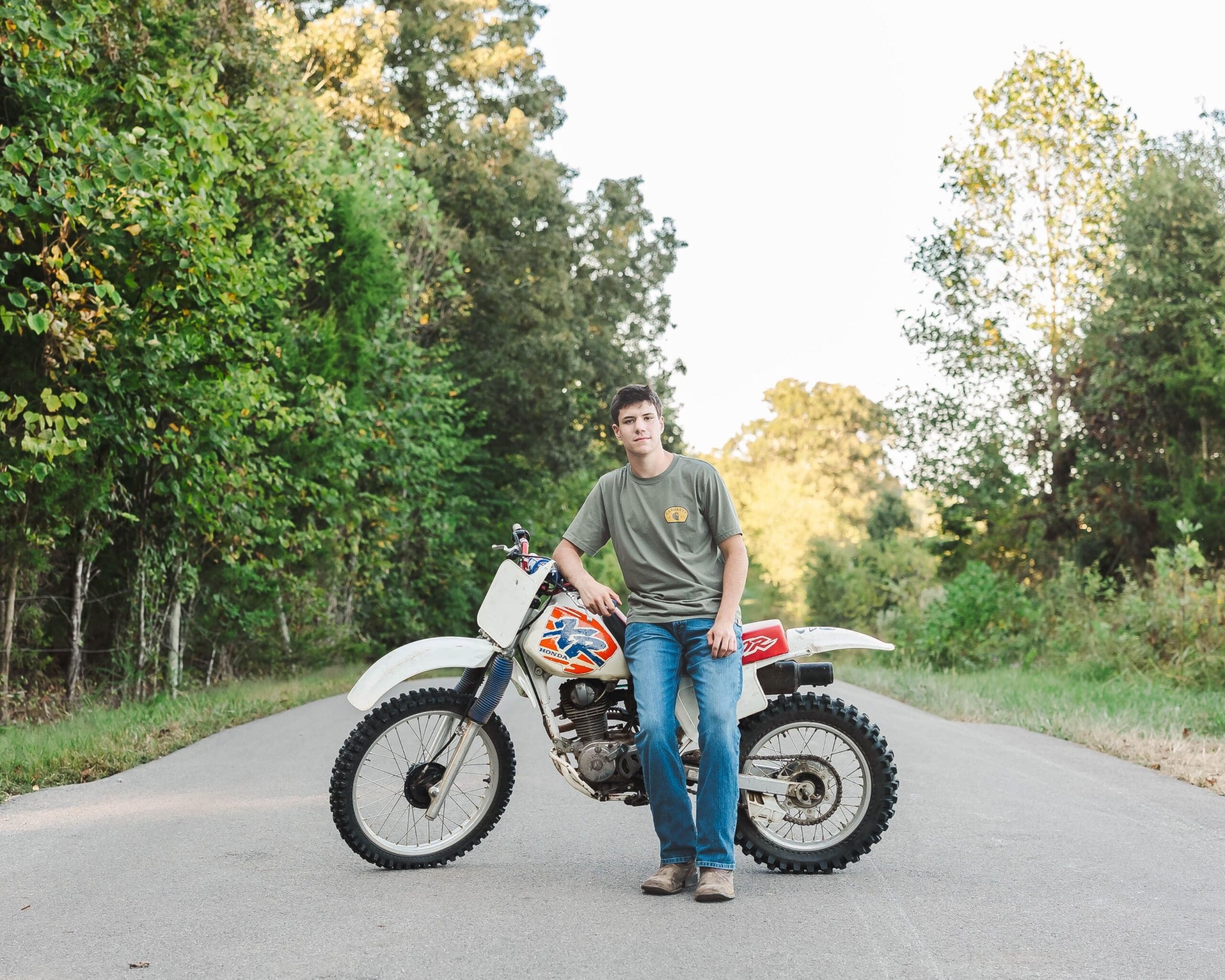 Bowling Green KY senior portraits of a high school senior standing beside his dirt bike in a rural field, shot by Jordan Z Photography